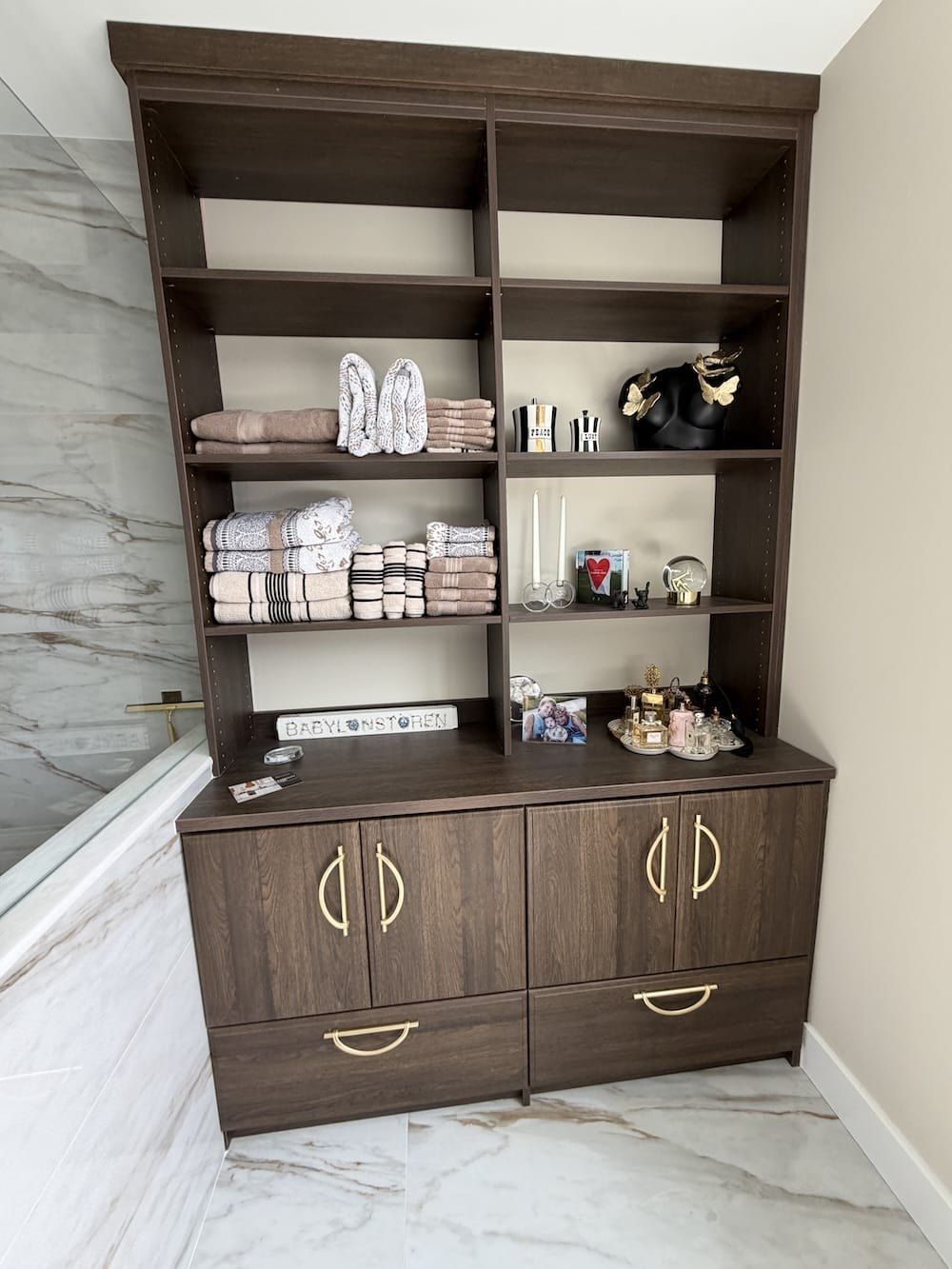 Dark wood built-in bathroom storage unit with open shelves and lower cabinets