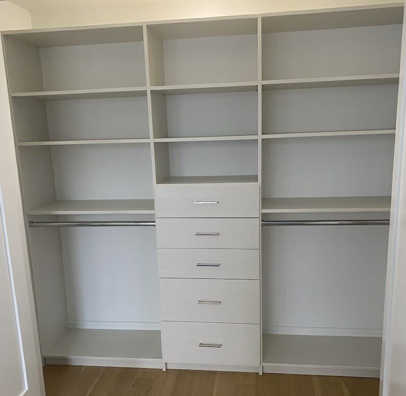 White closet with a five-drawer stack between hanging sections