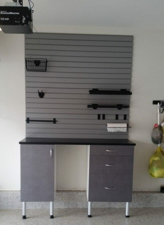 Garage workbench with drawers under a gray slatwall panel