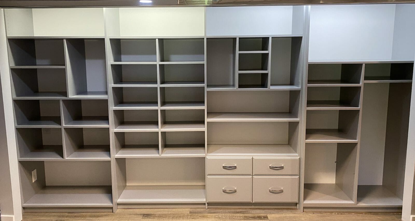 Long reach-in closet with gray shelving and a drawer bank