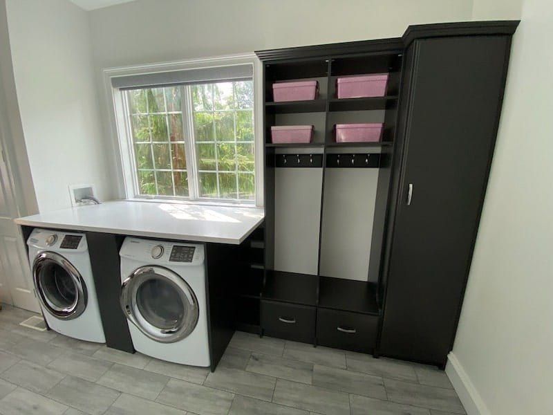 Laundry room with a folding counter over the washer and dryer next to mudroom lockers