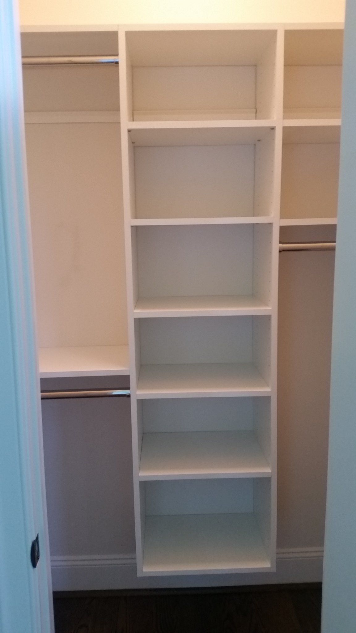 Reach-in closet with a white shelving tower and double-hang rods