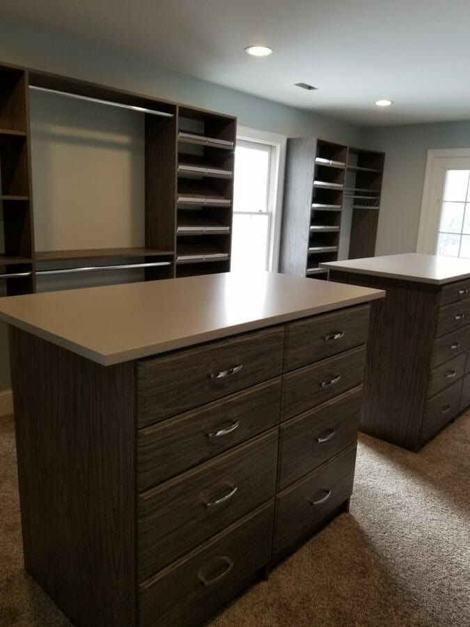 Walk-in closet with two dark wood-grain drawer islands