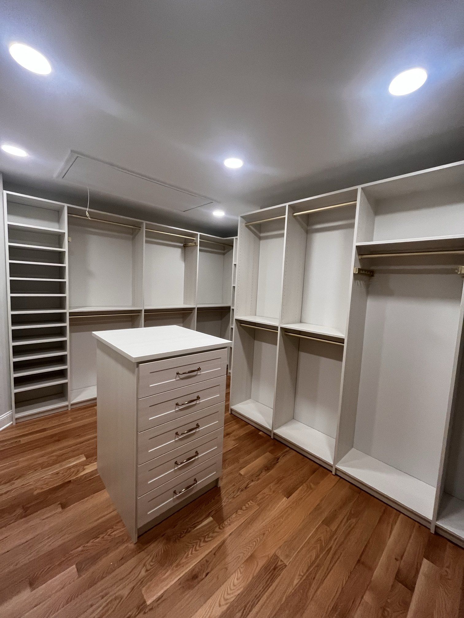 Walk-in closet with a drawer island, shoe shelving and hanging sections