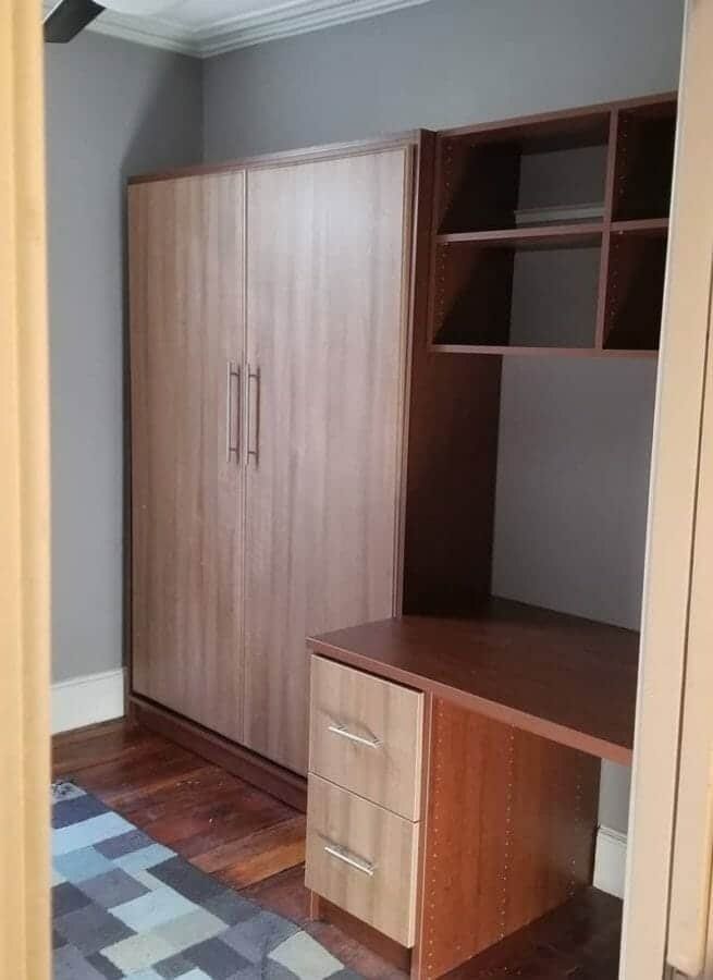 Wood-grain wall bed cabinet next to a built-in desk and shelving