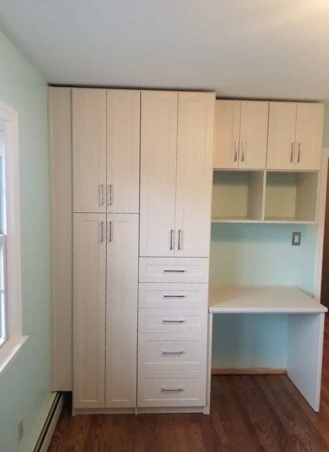 White home office with tall cabinets and a built-in desk