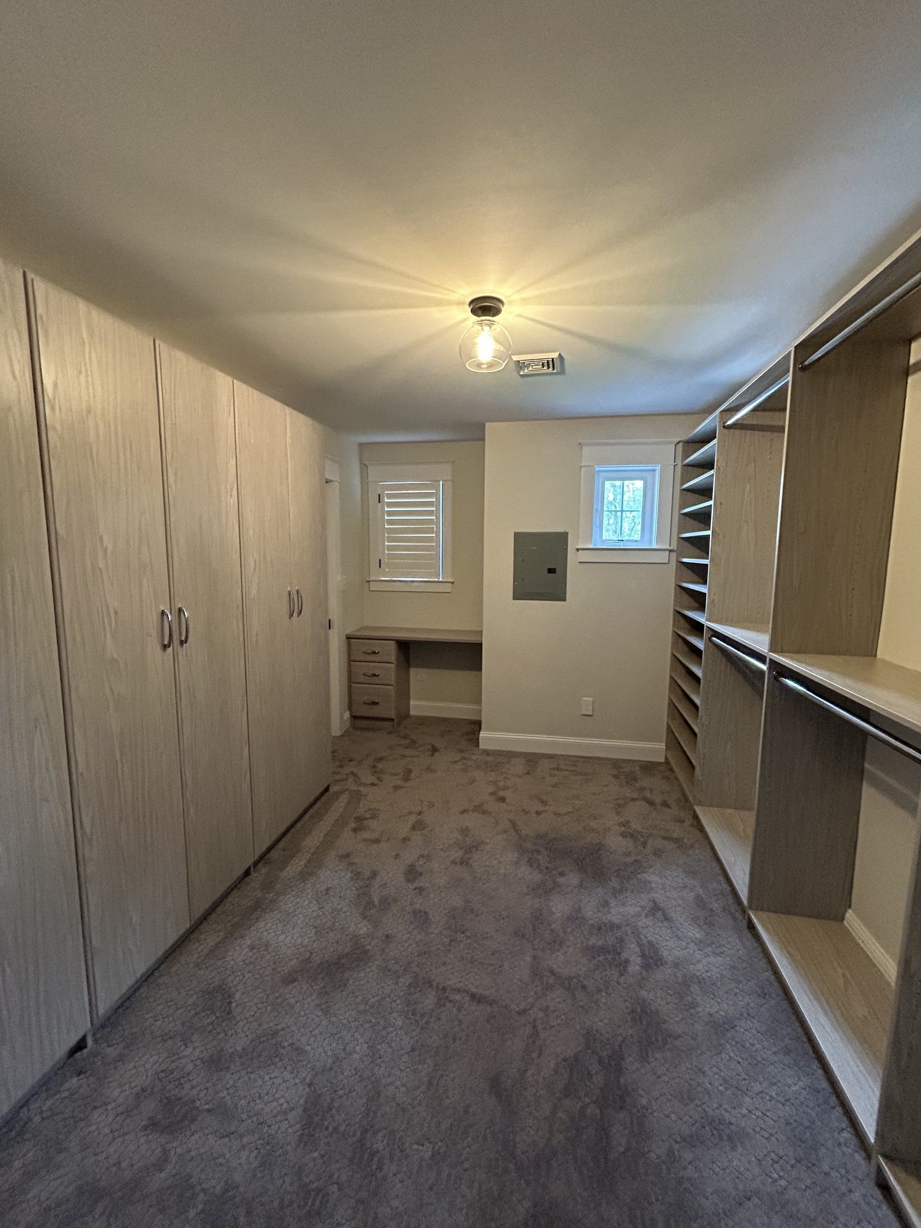 Walk-in closet with full-height wood-grain cabinets on one side and open shelving on the other